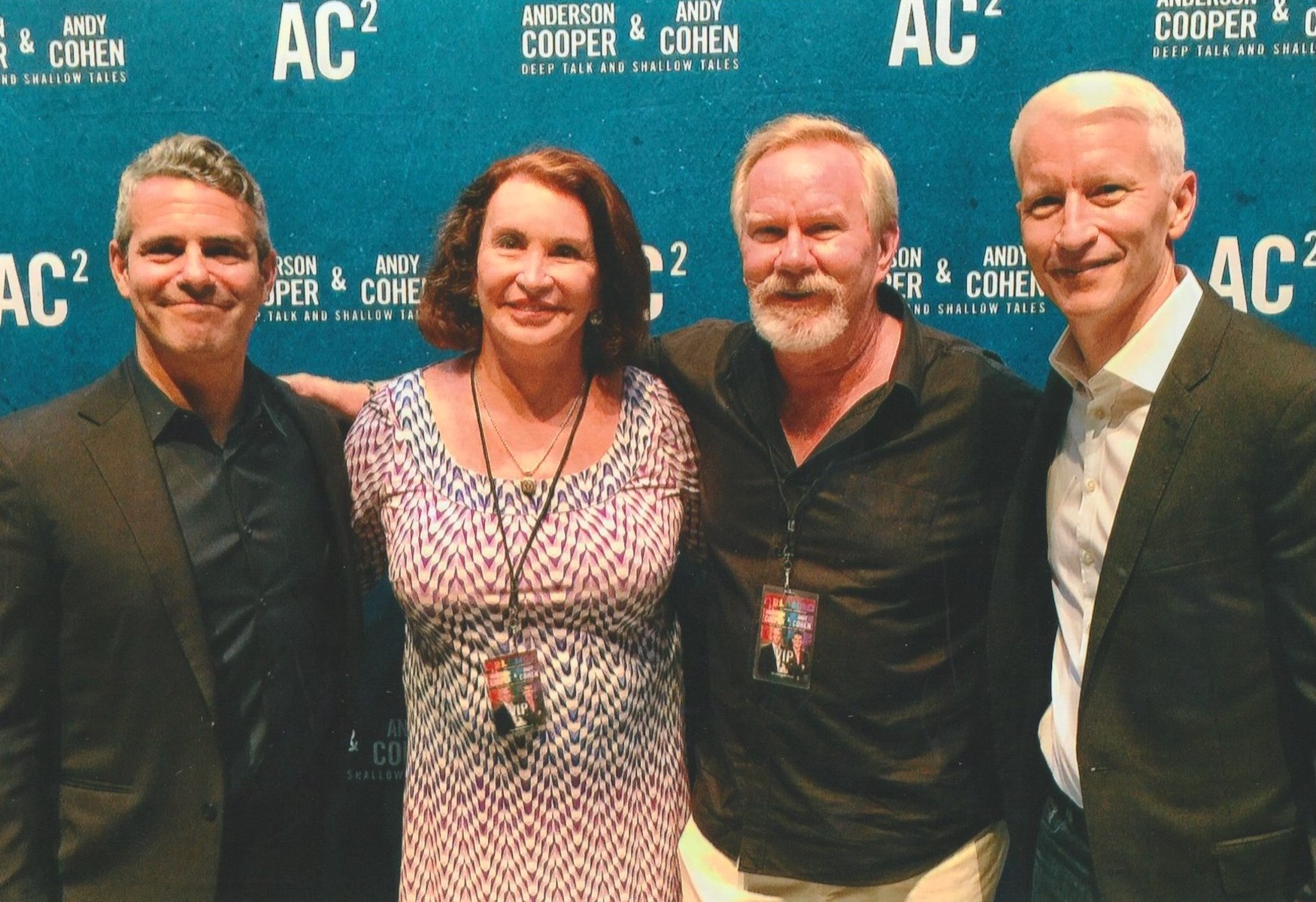 L-R: Andy Cohen, Gina Davis, Tom Dyer, and Anderson Cooper in front of the “Anderson Cooper & Andy Cohen: Deep Talks and Shallow Tales” promotional wall, Orlando, FL. Tom shares, “After the horrific Pulse massacre in 2016, in which 49 people lost their lives at an Orlando LGBTQ nightclub, Andy Cohen and Anderson Cooper brought their show to town to lift spirits. I’m pictured here with dear friend, Gina Davis, a remarkable transgender activist.” Photo courtesy of Tom Dyer.