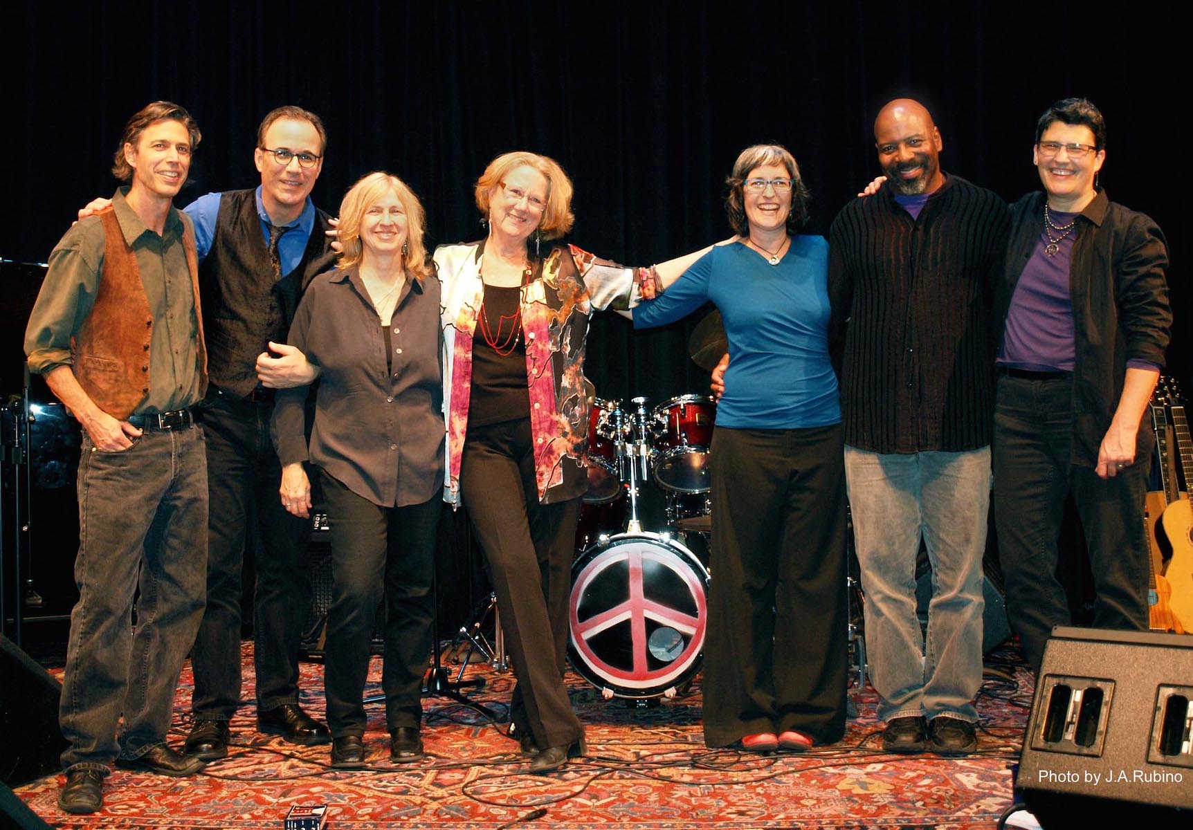 L-R: David Rokeach, John Bucchino, Jan Martinelli, Holly Near, Pat Humphries, Andre dos Santos Morgan, and Sandy O on the “Peace Becomes You” Tour, Freight & Salvage in Berkeley, CA, 2013. Photo Credit: J.A. Rubino. Photo courtesy of Holly Near.
