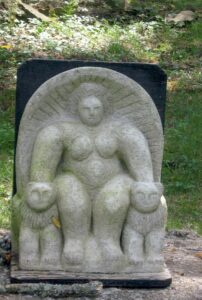A large clay sculpture of a figure holding two animals.