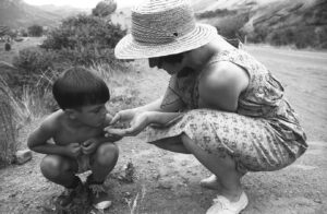 Diana showing her son Sean Folley a lizard in Colorado, as part of their cross country van trip, circa 1963.