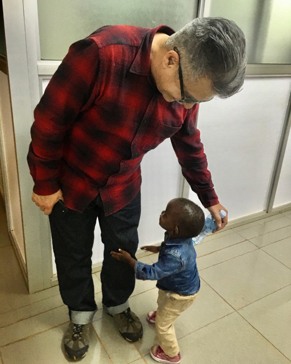 Joey Terrill in an AIDS Healthcare Foundation (AHF) clinic with a “beautiful affectionate child”, Kampala, Uganda, 2019.