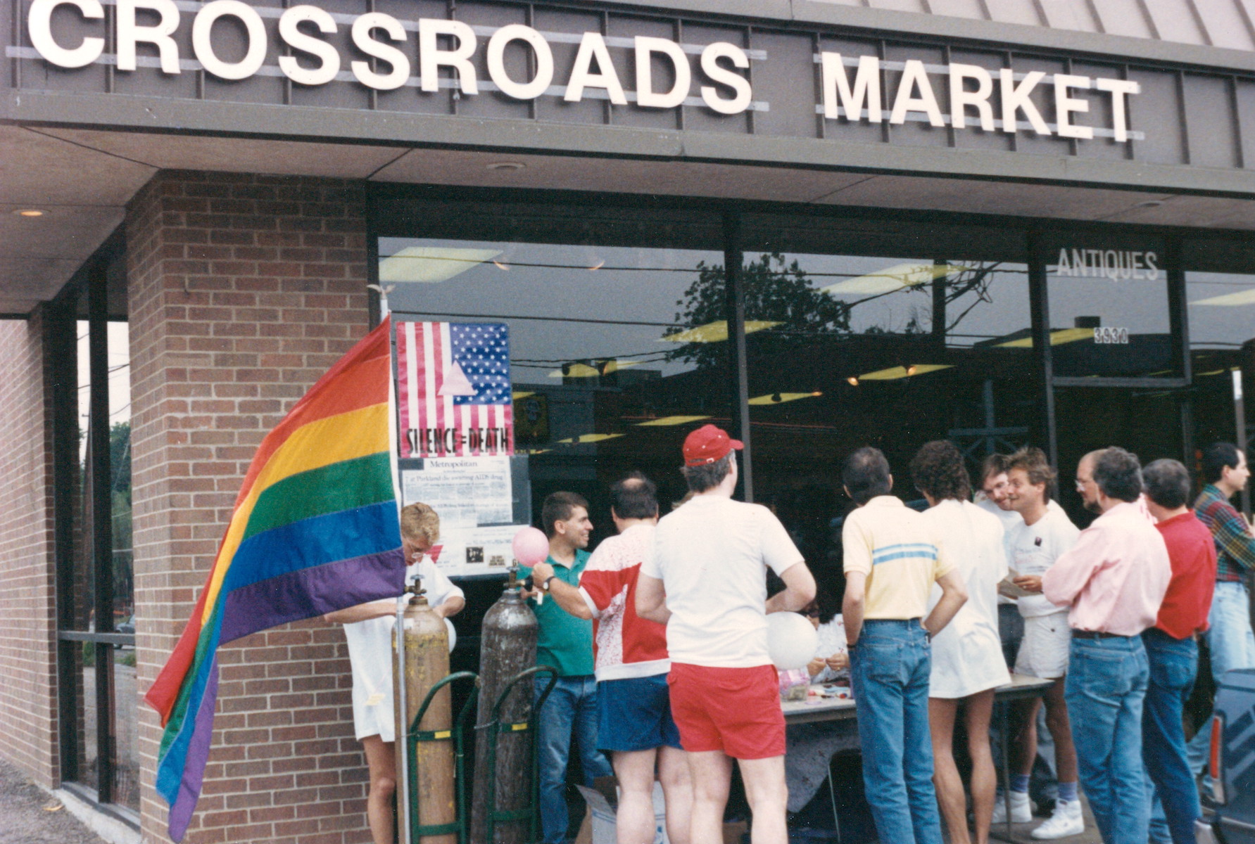 Gay activists gathered outside the Crossroads Market for an impromptu food drive, Dallas, TX, circa 1985. William shares, “In the 80s, our store was a hotbed of activism and political organizing – some group was out front every weekend recruiting volunteers for the next demonstration, working behind the scenes, etc. Many initiatives began inside the store. When Bill discovered that two guys with AIDS didn't have any food, he put a sign in the front window asking people to drop off a can of food. By the next morning, the entrance to the store was overwhelmed with packages of food. And again the next day, and the next, and finally we had so much food that we created a food bank that is still in existence today. The community responded in ways we never imagined.” Photo courtesy of William Waybourn.