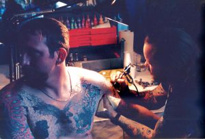 Randy Adams (deceased) tattoos a left arm sleeve on Doc Duhon, 1985, Seattle, WA.