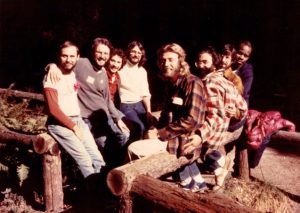 Group photo of eight men on railings, Tom Mosmiller pictured in center, 1978. This photo was taken at the 1978 San Francisco Bay Area Planning Committee for the 1st California Men's Gathering of pro-feminist, gay affirmative, anti-racist men.