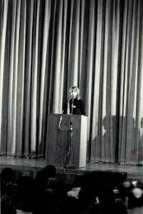 Tom Mosmiller at a podium delivering a keynote speech at the 14th National Men and Masculinity Conference titled “MENERGY: Celebrating the Pro-Feminist Men's Movement”, 1989, Pittsburgh, PA. His keynote speech was 