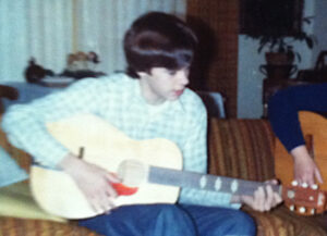 Chris Freeman, playing the acoustic guitar he learned on, with his cousin Julie at his Aunt Betty’s house, summer 1975. He shares, “We were probably playing Beatles’ songs.” Photo courtesy of Chris Freeman.