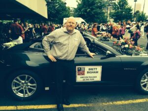 Brett standing next to a car that reads, “Brett Bigham: Oregon Teacher of the Year”, for the Rose Festival’s Grand Floral Parade, Portland, OR, 2014. Photo Credit: Mike Turay. Photo courtesy of Brett Bigham.