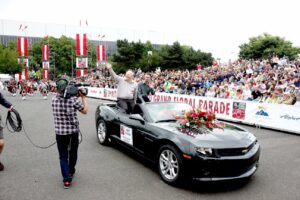 Brett and his husband Mike Turay waving to the crowd while riding in the Rose Festival’s Grand Floral Parade, Portland, OR. Photo Credit: The Rose Festival. Photo courtesy of Brett Bigham.