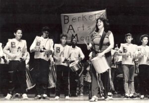 Child musicians from the Berkeley Arts Magnet School, wearing jumpers with BAM written across diagonally, and Carolyn playing a concert, 1985. Photo courtesy of Carolyn Brandy.