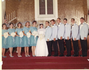 L-R: Five bridesmaids (in teal dresses), Judy Abdo, husband Joseph Abdo, and five groomsmen (in light blue and black suits) pose at the Abdo wedding, First Presbyterian Church of Hollywood, Los Angeles, CA, July 4, 1964. Photo courtesy of Santa Monica Public Library Image Archives, Judy Abdo Photo Album Collection.