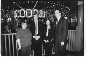 Judy Abdo (left), Nancy Greenstein (third from left) and others in front of a carousel at a Santa Monica Pier event, 1990s. Nancy Greenstein's public sector positions include Council Deputy and Public Safety Administrator for West Hollywood. She's also a member of the Santa Monica College Board of Trustees. Photo courtesy of Santa Monica Public Library Image Archives, Judy Abdo Photo Album Collection.