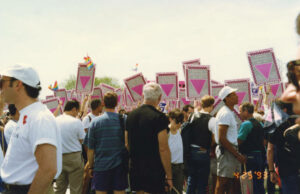 Attendees hold March on Washington-branded signs and pride flags at the March on Washington for Lesbian, Gay, and Bi Equal Rights and Liberation, Los Angeles, CA, April 25, 1993. The signs read, “March on Washington, Liberty and Justice For All” across top, “Lesbian, Gay, and Bi Equal Rights and Liberation” at left, “Unity, Diversity, Solidarity” at right, and “April 25, 1993, Los Angeles, CA” at bottom, with a pink triangle at center and feature a pink triangle at center. Photo taken by Judy Abdo, and courtesy of Santa Monica Public Library Image Archives, Judy Abdo Photo Album Collection.