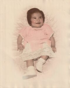 A baby portrait of Terri, around six-months old, in a pink and white lace dress, 1947. Photo courtesy of Terri de la Peña.