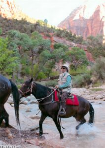 Terri riding a horse through a river in Zion National Park, UT, August 13, 2013. Terri shares, “This was two months after I retired from UCLA.” Photo courtesy of Terri de la Peña. 	