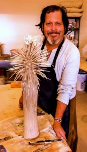 Miguel posing with his sculpture of “Joshua Tree in Bloom”, which was handmade with porcelain, Palm Springs, CA, 2017. Photo courtesy of Miguel Criado.