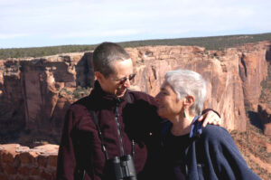 L-R: Barbara Byers (Margaret’s partner) and Margaret hugging and smiling at the Canyon de Chelly National Monument in Apache County, AZ, 2005. Photo courtesy of Margaret Randall.