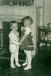 Esther and her brother holding hands while smiling and wearing Austrian outfits, likely in Madrid, Spain, circa 1961. Photo courtesy of Esther Rothblum.