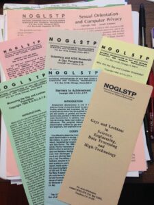 A stack of various NOGLSTP pamphlets, which were funded by a Chicago Resource Center grant and published from 1986-1994, for education on LGBTQ STEM issues. Titles read “Sexual Orientation and Computer Privacy” (printed on orange paper) “Computer Lists and Gays: Some Things You Should Know” (printed on pink paper), “Scientists and AIDS Research: A Gay Perspective” (printed on gray paper), “Who are the Gay and Lesbian Scientists?” (printed on yellow paper), “Measuring the Gay and Lesbian Population” (printed on green paper), “Barriers to Achievement” (printed on blue paper), and “Gays and Lesbians in Science, Data Engineering, Data Processing and High Technology” (printed on brown paper). Photo courtesy of Shelley Diamond.

