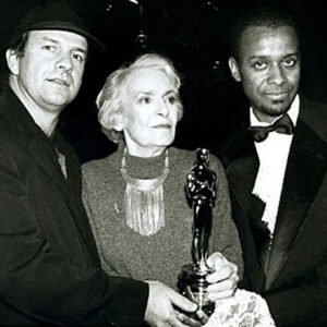Paul Outlaw (right), director Pepe Danquart (at left), and lead actress Santa Moira (at middle, holding the award) celebrating Schwarzfahrer’s Oscar win as Best Live Action Short Film at the Grand Hotel Esplanade in Berlin, Germany, 1994. Photo courtesy of Paul Outlaw. 
