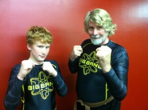 Mike and his nephew Donovan in karate poses, January 2011. Their shirts read, “Big Bang”, inside of neon green atoms. Photo courtesy of Mike Szymanski. 