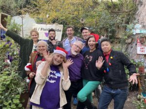 Mike and other Los Angeles Bi+ Task Force Members, Hollywood, CA, December 2022. He shares, “I’m back in activism through serving on the board of the Los Angeles Bi+ Task Force. Here, we’re goofing around at my holiday party in my backyard.” His shirt reads, “Love Beyond Gender”. The banner in the background reads, “Bi / Fluid Pride.” Photo courtesy of Mike Szymanski.