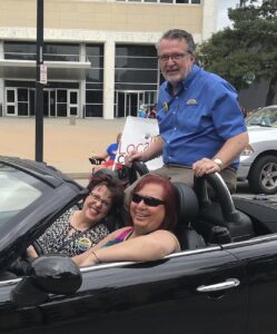 Stephanie Byers (at the driver’s wheel) drives then Kansas Lieutenant Governor, Lynn Rogers (backseat) and his wife Kris (passenger, front seat) in the Wichita Pride Parade, Wichita, Kansas, 2019.  Photo courtesy of Stephanie Byers.