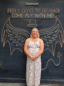 Stephanie poses in front of angel wings with devil horns “Feels good to be bad! Come fly with me!” mural. At the LGBTQ Leaders of the Americas and Caribbean Conference in Mexico City, Mexico, 2023. Photo courtesy of Stephanie Byers.