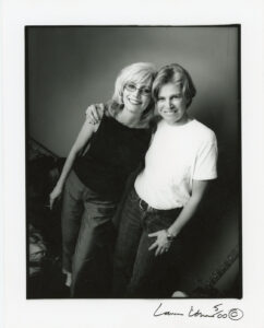 Grayscale photo of Cidny Bullens and Emmylou Harris smiling and hugging backstage at one of Cidny’s shows, Nashville, TN, 2000. Photo courtesy of Cidny Bullens.