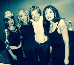 High contrast blue-toned photo of Cidny Bullens (second from R), Lucinda Williams, Emmylou Harris and Julie Miller at Cidny’s show in Nashville, TN, 2000. Photo courtesy of Cidny Bullens.