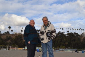 Gerald Gerash and Ron Gold, Media Director of the National Gay Task Force, smiling and wearing wool jackets on a beach in Santa Monica, California, 2013. Photo courtesy of Gerald Gerash. 