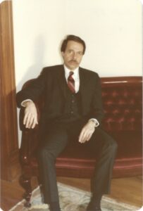 Gerald sitting on a velvet sofa in a three piece suit, at his home in Denver, Colorado, 1981. Photo courtesy of Gerald Gerash. 