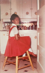 Betty at age 7, sitting on a stool in the kitchen. Photo courtesy of Betty Berrysmith.