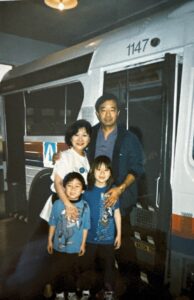 Family photo outside of a bus (L-R, clockwise): Marsha Aizumi, father Tad, Aiden, and brother Stefen. At a Children’s Museum in La Habra, CA, circa 1994. Photo courtesy of Marsha Aizumi.