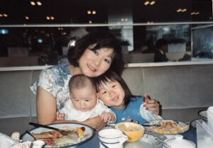 Marsha hugging baby brother Stefen and young Aiden Aizumi at a restaurant after the family “picked up Stefen from an adoption agency.” Tokyo, Japan, 1991. Photo courtesy of Marsha Aizumi.