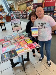 Videotaped photo still of Marsha and Aiden Azumi smiling together at a Barnes and Noble bookstore, holding up their book “Two Spirits, One Heart.” Los Angeles, CA, 2022. Photo courtesy of Marsha Aizumi.