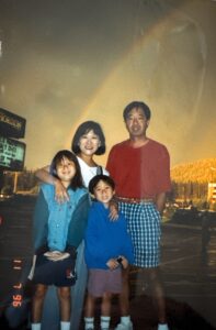 Family photo in front of a luminous rainbow (L-R) Marsha, father Tad, brother Stefen, and Aiden Aizumi. Lake Tahoe, CA, 1995. Photo courtesy of Marsha Aizumi.