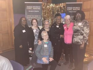 Harriet Miller and Monica Wehrle (back and front center) smile with their Fort Wayne Women’s Bureau staff at a festive, reunion celebration. Fort Wayne, Indiana, 2023. Photo Courtesy of Harriet Miller and Monica Wehrle.