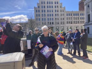Monica Wehrle at a protest rally outside big concrete buildings in Fort Wayne, Indiana, 2023. Photo Courtesy of Harriet Miller and Monica Wehrle.