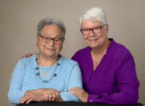Harriet Miller and Monica Wehrle both wearing glasses while smiling and gently holding each other, side by side. In Fort Wayne, Indiana, 2020. Photo Courtesy of Harriet Miller and Monica Wehrle.
